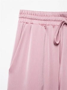 Detail van een oudroze broek met elastische taille met trekkoord en geplooide stofstructuur