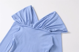 Detail of light blue knit top featuring cross-fold draped neckline and soft fabric texture