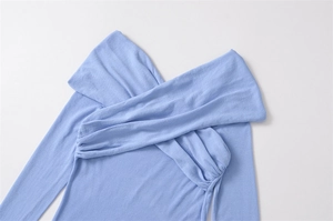 Detail of light blue knit top featuring a unique criss-cross V-neck and soft texture