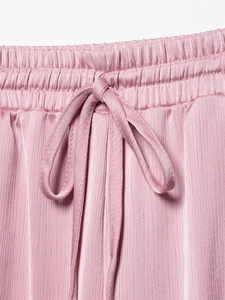 Macrodetail van de roze geplisseerde broek met elastische tailleband en trekkoord