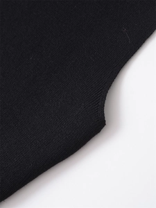 Macro detail of high-quality black knitted fabric showing fine texture and hem finishing