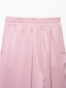 Detail van roze satijnen broek met hoge elastische taille en gladde zijden textuur