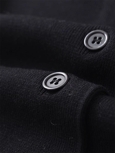 Close-up of fine knit black fabric featuring decorative buttons with silver metal trim