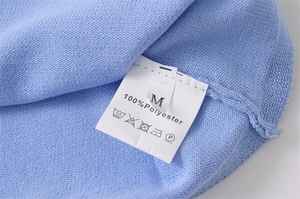 Detailed close-up of garment care label showing 100% polyester fabric and size M