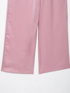 Detail van een roze satijnen broek met wijde pijpen en een gladde verticale textuurglans