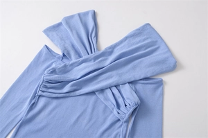 Detailed close-up of light blue off-shoulder knit top with cross-wrap neckline design