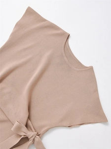 Dettaglio maglia a coste morbida beige con elegante fiocco laterale e scollo rotondo