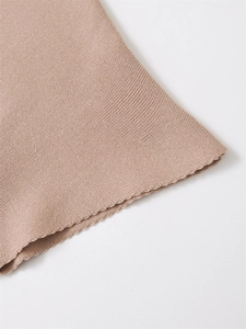 Dettaglio in primo piano del tessuto in maglia beige con bordo smerlato a onde
