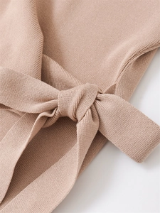 Dettaglio di un top in maglia beige con nodo in tessuto e trama fine di qualità