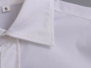 Détail du col d'une chemise blanche en coton montrant l'étiquette S et les doubles coutures