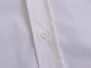 Détail de la patte de boutonnage de chemise blanche avec coutures nettes et bouton rond