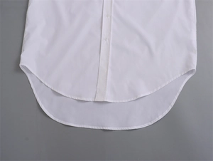 Détail d'une chemise blanche avec ourlet arrondi asymétrique et patte de boutonnage