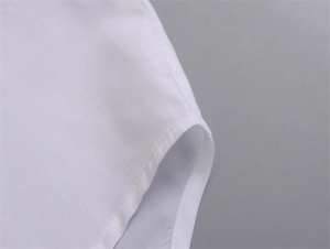 Gros plan détaillé montrant les coutures précises et l'ourlet de la chemise blanche