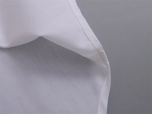 Détail macro des coutures de haute qualité sur l'ourlet du chemisier en coton blanc