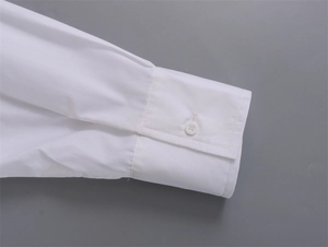 Détail du poignet d'une chemise blanche en coton avec un bouton en résine poli