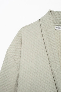 Close-up of textured light green V-neck top showing premium crinkle fabric and brand label