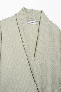 Detailed view of the crinkle textured fabric and V-neckline of this sage green top