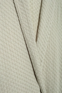 Detailed macro view of beige textured crepe fabric with elegant layered collar structure
