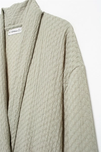 Detailed macro view of sage green seersucker textured fabric and interior neck brand label