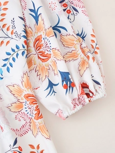 Detail der elastischen Manschette am weißen Blumenkleid mit orangefarbenem Muster
