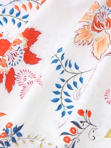 Detailaufnahme von Sommerkleid-Stoff mit orangefarbenen Blumen und blauen Blättern