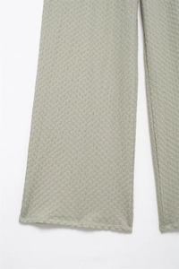 Detailed macro view of sage green textured fabric on straight-leg casual trousers