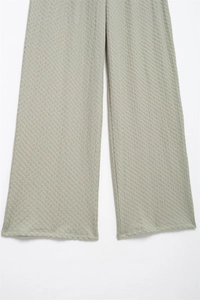 Close-up of sage green textured wide-leg pants showing fabric drape and hem detail