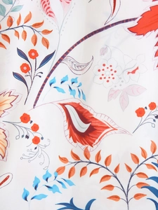 Detail von böhmischem Blumendruck mit orange-blauen Blättern auf weißem Kleid