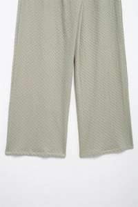 Detail of light sage green wide-leg trousers featuring a textured diamond jacquard fabric