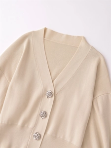 Detail of elegant silver rose-shaped metal buttons on a beige knit cardigan sweater