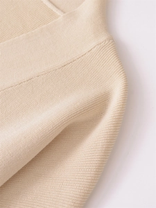 Detailed close-up of beige knit fabric showing smooth plain stitch texture and ribbed edges