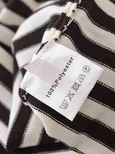 Nahaufnahme des Pflegeetiketts mit 100% Polyester und Größe M auf gestreifter Strickware
