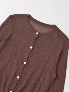 Detailed shot of dark brown textured knit cardigan featuring white pearlescent buttons