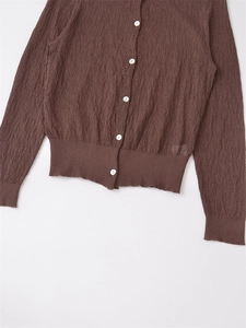 Close-up of deep brown seersucker cardigan with white buttons and ribbed texture details