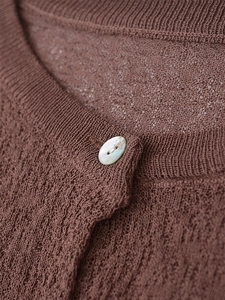 Close-up of brown knit cardigan neck with natural shell button and fine texture