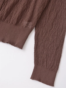 Detail showing the brown knit cardigan's pleated texture and ribbed cuffs on white background