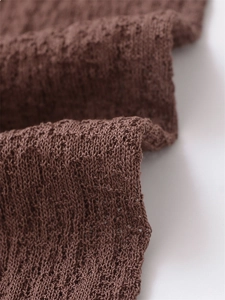 Close-up of brown hollow crochet knit fabric with intricate texture and soft fiber details