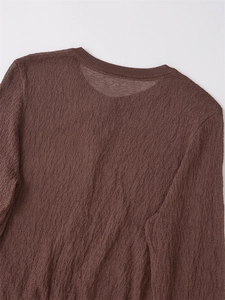 Close-up of the textured knit fabric and ribbed round neckline of the brown cardigan