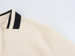 Detail des cremefarbenen Polo-Sweatshirts mit schwarz-weiß gestreiftem Rippkragen und Strickstruktur