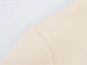 Detailansicht der Schulternaht und feinen Strickstruktur des beigefarbenen Polo-Sweatshirts