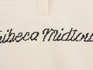 Detail der Tribeca Midtown Kreuzstich-Stickerei auf cremefarbenem Strick-Polo-Sweatshirt