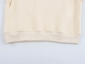 Detaillierte Nahaufnahme des Rippsaums an einem cremefarbenen Sweatshirt mit feinen Nähten
