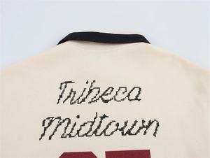 Detail der Tribeca Midtown Stickerei auf dem cremefarbenen atmungsaktiven Poloshirt