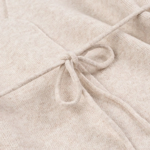 Detalle de cárdigan de punto beige mostrando el lazo en la cintura y la textura