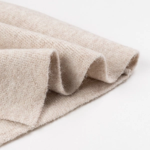 Primer plano de suave tejido de punto beige con textura de lujo y detalles de fibra
