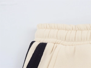Detail der cremefarbenen Jogginghose mit elastischem Bund und Seitenstreifen