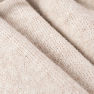 Detalle macro de tejido de punto beige suave que muestra textura y fibra de lana fina