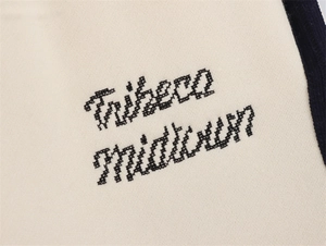Detailaufnahme der Tribeca Midtown Stickerei auf cremefarbenem Stoff mit Paspelierung