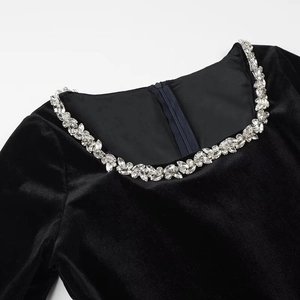 Detail of square neckline on black velvet dress with shimmering crystal embellishments