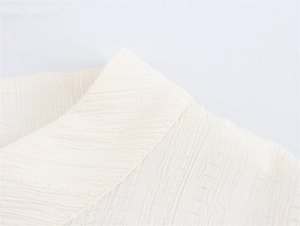 Detailaufnahme von cremefarbenem Jacquard-Stoff mit feinen Nähten am kleinen Stehkragen